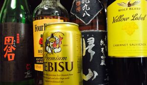 Shochu, whiskey, nihonshu, and wine in the back row, with a can of beer in front.